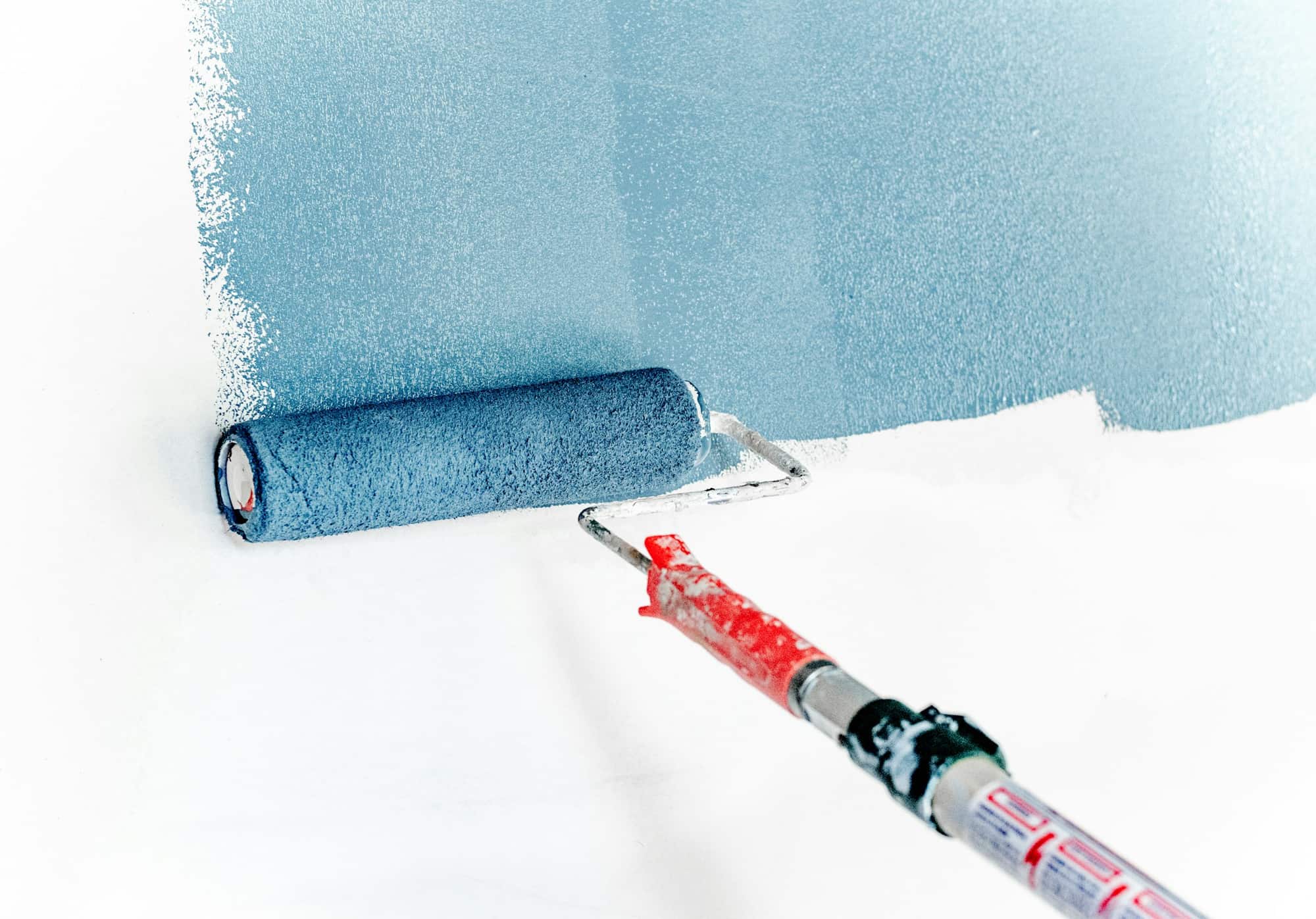 Blue paint roller on an extension pole against a white wall