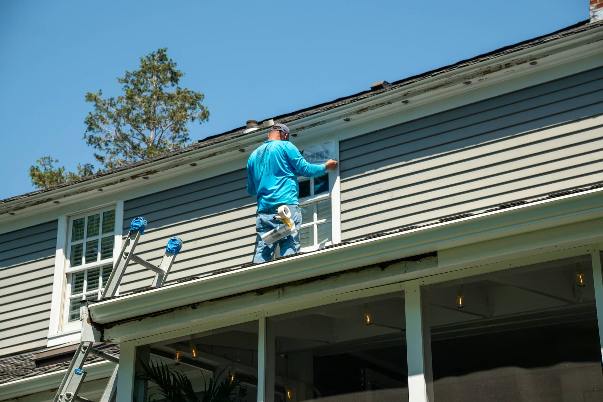 Person painting the exterior wall of a house